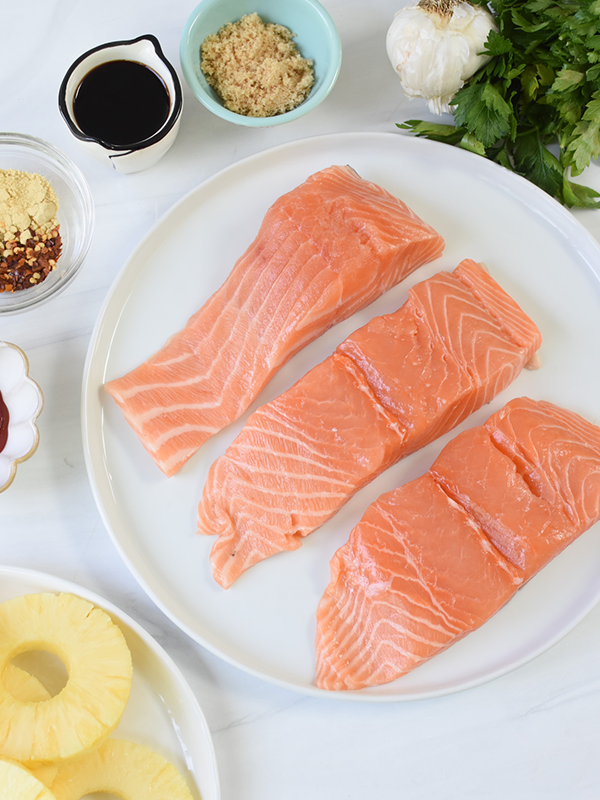 Ingredients for Hawaiian Grilled Salmon including, fresh salmon fillets, ginger, soy sauce dry seasonings, pineapple, onion and cilantro.