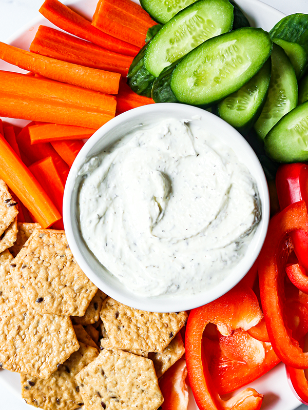 Greek yogurt dip served with cucumbers, carrots, bell peppers and crackers.