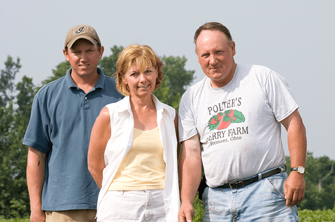 Three Members of the Polter Family Standing in a Produce Field