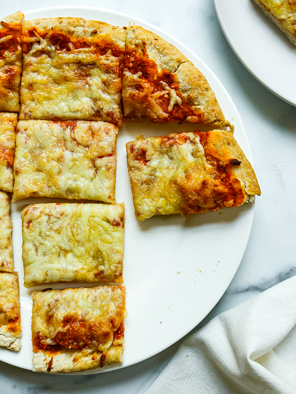 Marinara and cheese flatbread pizza cut into squares and served on a plate.