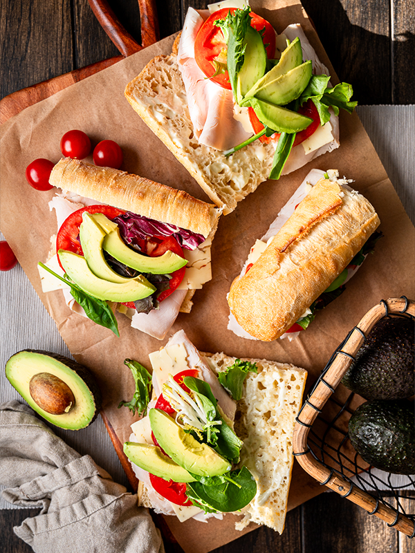Roasted Turkey Sandwich topped with sliced avocado, tomatoes and spring mix.