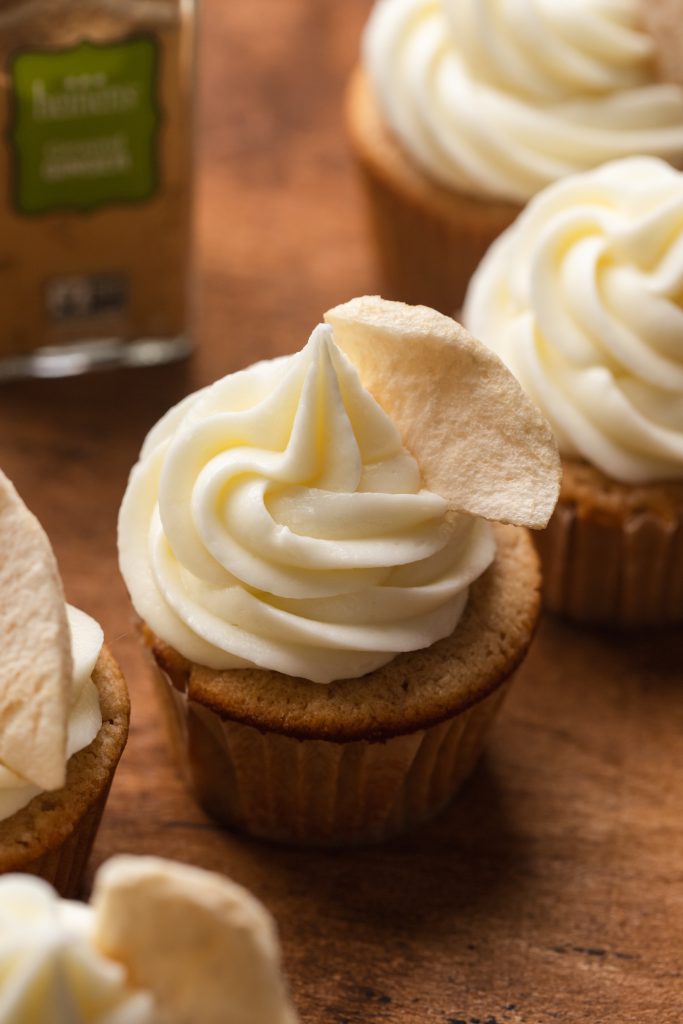 Apple Spice Cupcakes topped with icing and a dried apple crisp.