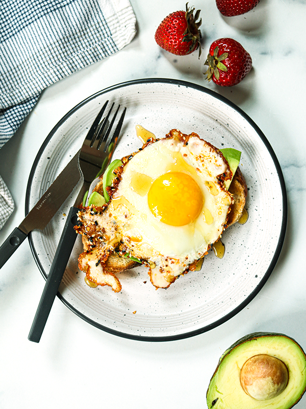Avocado toast topped with an egg and served on a plate.