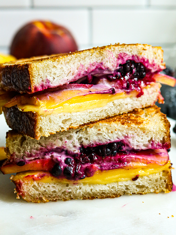 Plant-based grilled cheese with blackberries and peaches sliced in half and served on a plate.