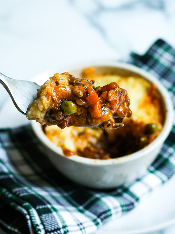 Spoonful of cottage pie over a bowl of cottage pie.