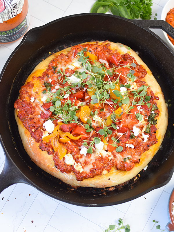 Overhead view of a red pepper pizza in a cast iron skillet.