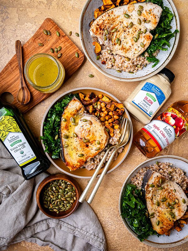 Swordfish Grain Bowls surrounded by ingredients including olive oil, Dijon mustard, seeds, and apple cider vinegar.