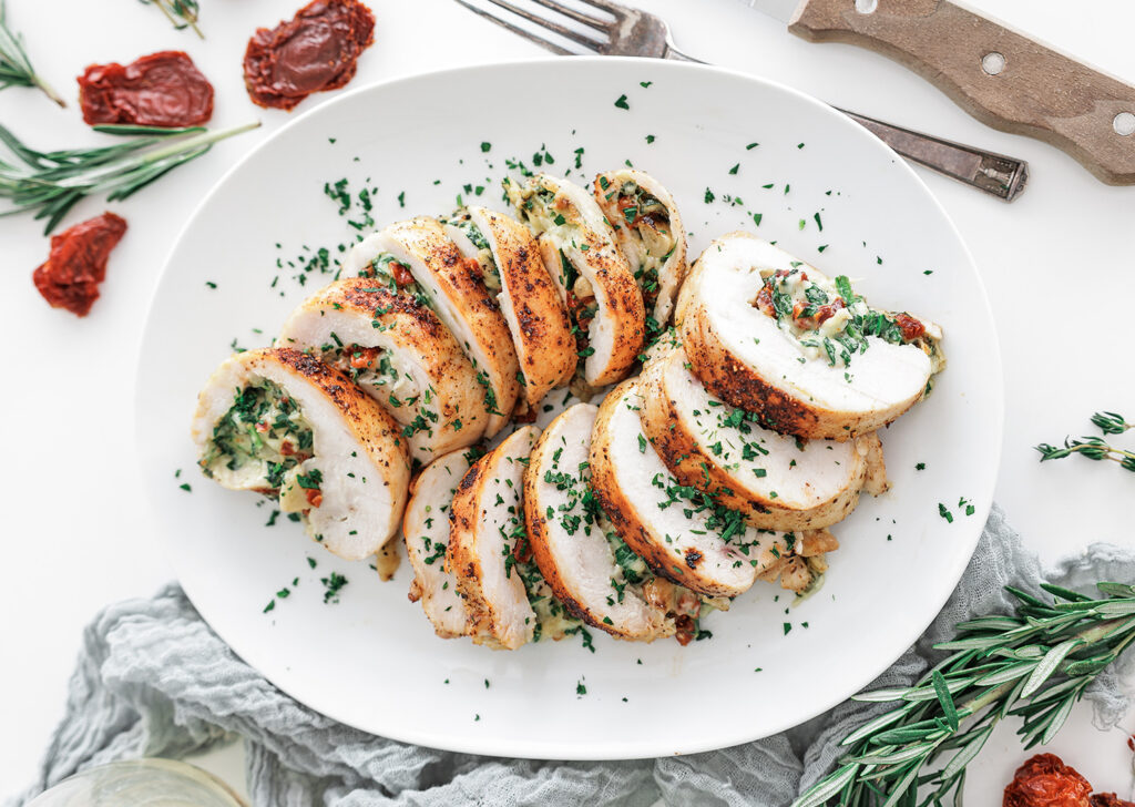 Stuffed turkey breast on a plate, garnished with herbs.