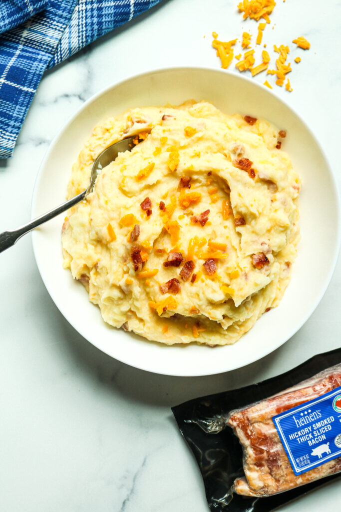 Elevated mashed potatoes served in a bowl with bacon and shredded cheese.