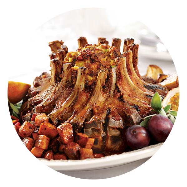 Heinen's Pork Crown Roast with stuffing in the middle, surrounded by potatoes and herbs.