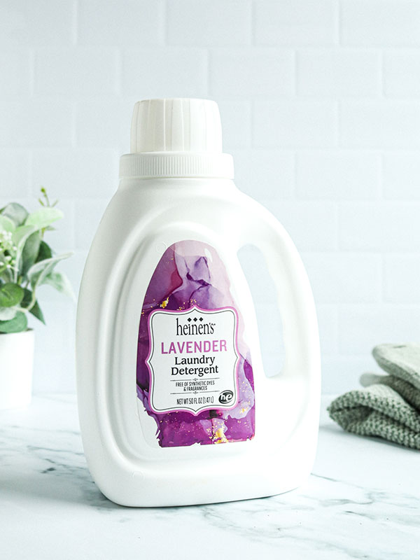 Heinen's Lavender Landry Detergent Bottle with a Green Plant and Fresh Towels