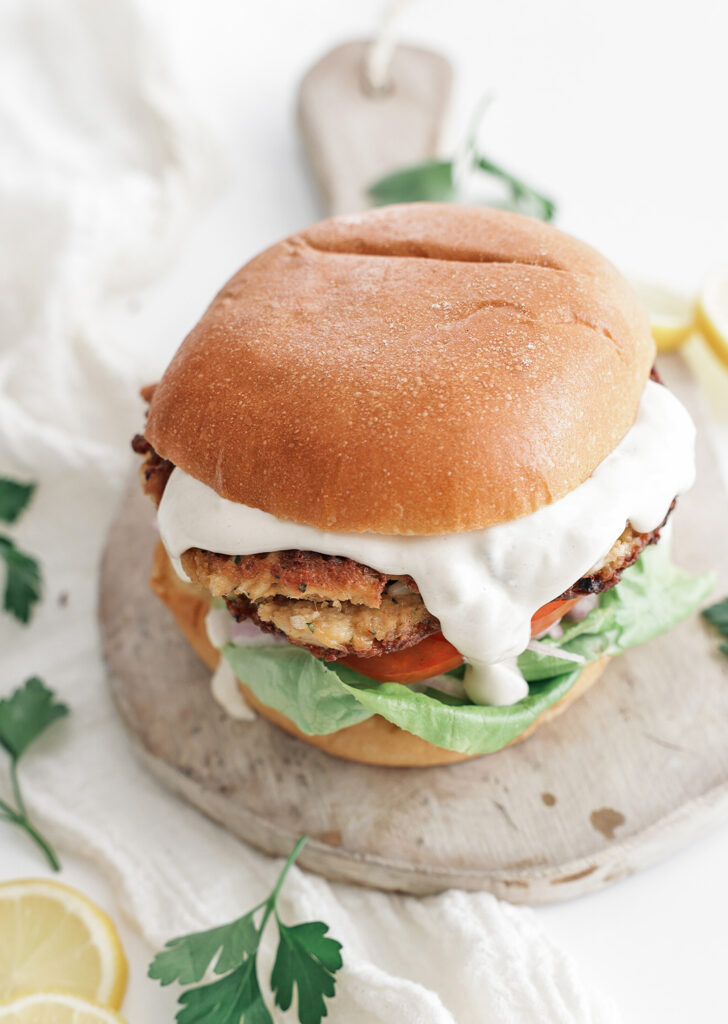 Crab cakes served on a bun with lettuce, tomato, and aioli dressing.