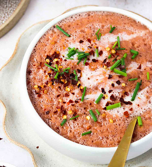 Red Summer Gazpacho in a Bowl with a Gold Spoon