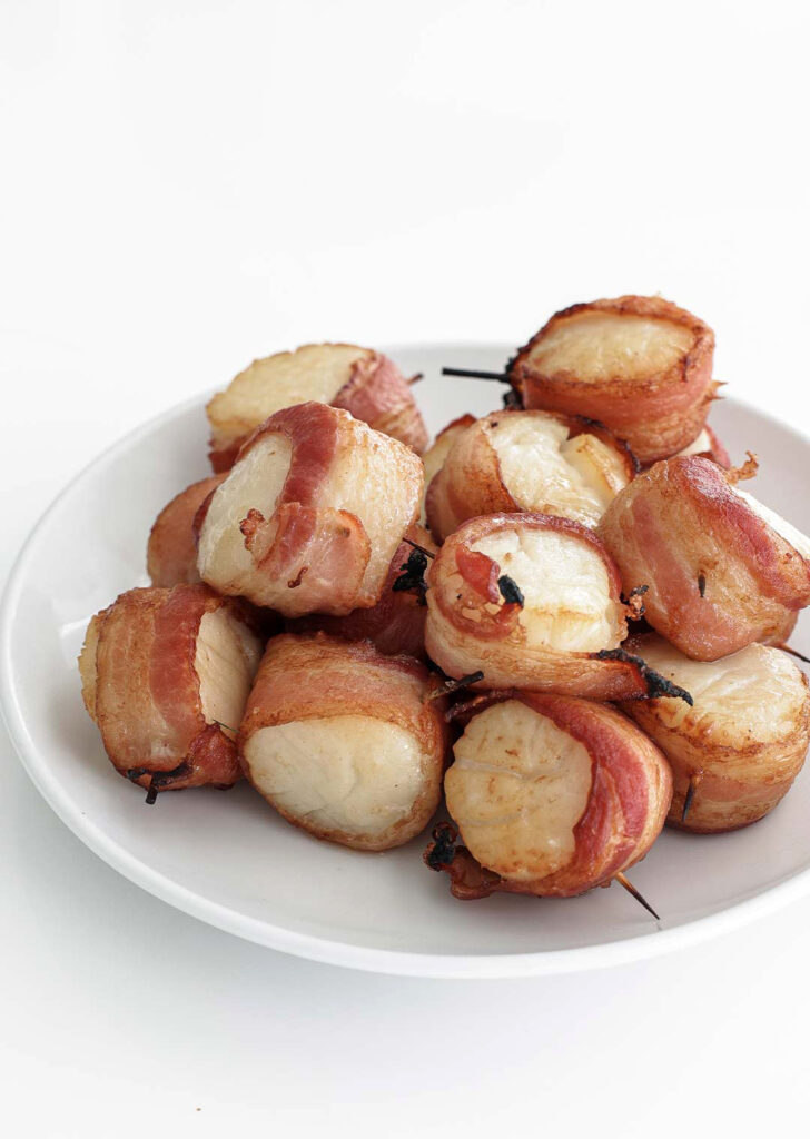 Bacon wrapped scallops served on a plate.