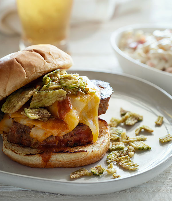 Vertical Image of an BBQ Meatloaf Sandwich on a Plate with a Glass of Beer and a Bowl of Macaroni Salad