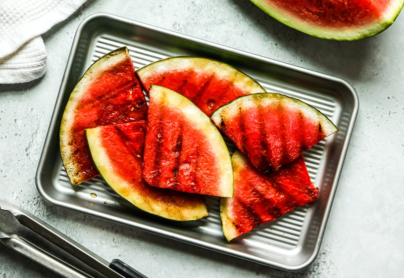 Overhead view of grilled watermelon on a sheet pan.