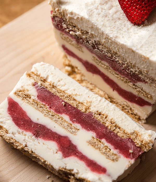 Ice cream cake with layers of vanilla ice cream, strawberry puree, and graham crackers.