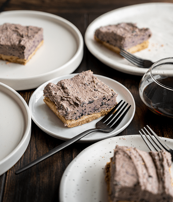 An Assortment of Blueberry Bars on Round White Plates with Forks