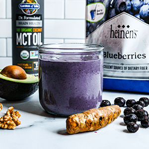 A Purple Brain Boosting Smoothie in a Glass with Fresh and Frozen Produce Surrounding