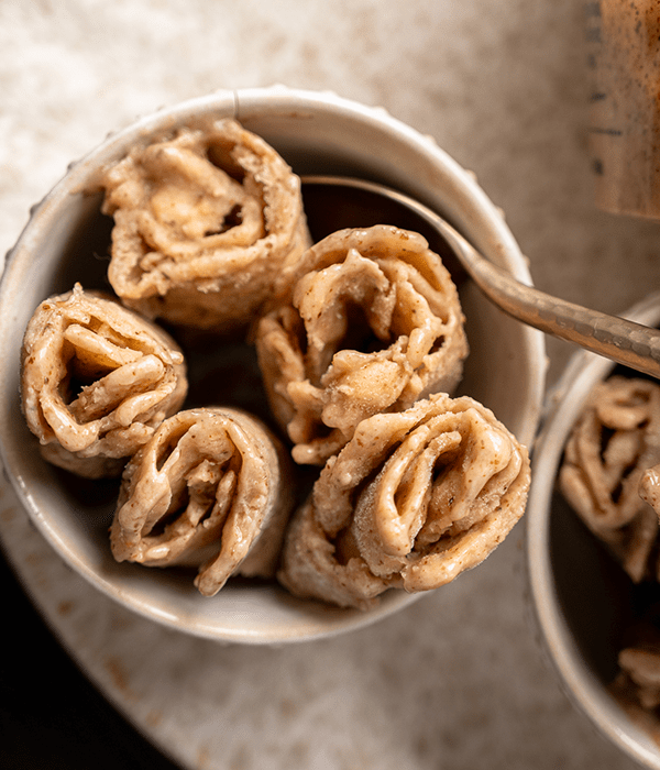 A Close Up Image of Several Vanilla Almond Frozen Rolls in a Small White Serving Bowl