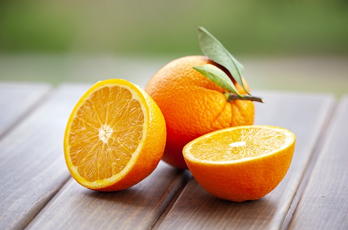 2 oranges, one halved and one whole, on a picnic table