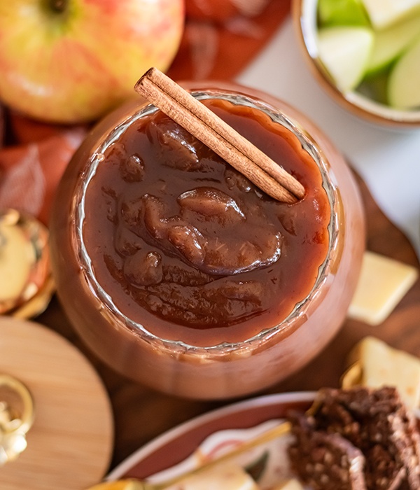 An overhead view of a jar of apple butter with a cinnamon stick.