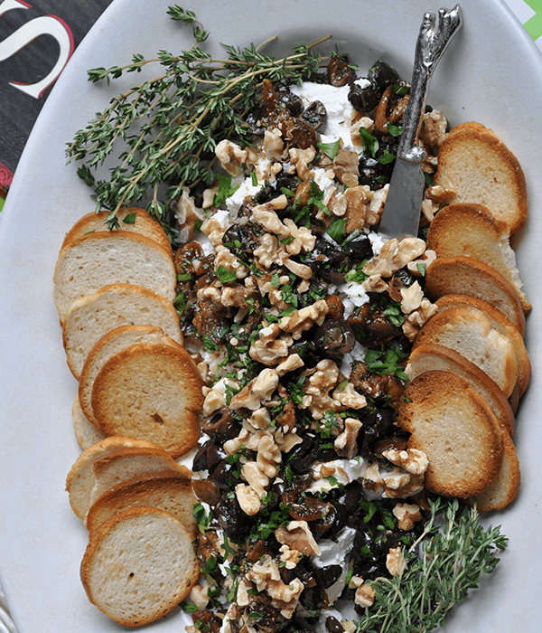 Fig-and-Walnut-Tapenade-with-Goat-Cheese on a Serving Platter with Crackers and Fresh Herbs