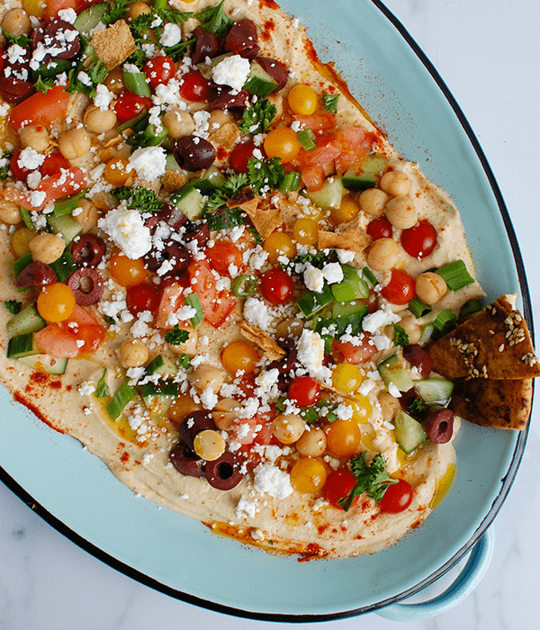 A Serving Bowl of Full of Homemade Hummus with Colorful Greek Inspired Toppings