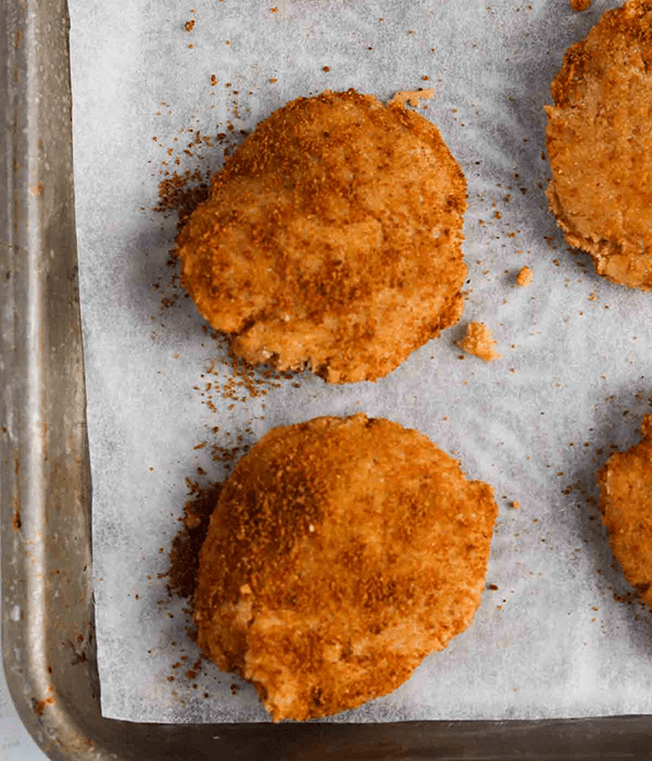 Two Baked Snickerdoodle Cookies on a Parchment-Lined Baking Sheet