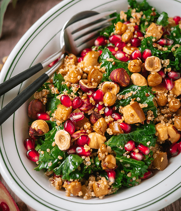 Kale-Quinoa-Winter-Salad-with-Pears-and-Pomegranate on a Serving Platter with a Serving Spoon and Fork