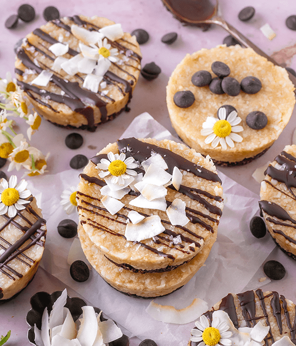 An Array of No-Bake Coconut Cups Drizzled in Chocolate and Topped with Edible Flowers