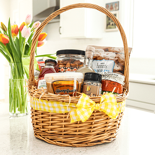 A Wicker Basket with a Handle and Yellow Ribbon Filled with Various Food, Snacks and Self Care Items
