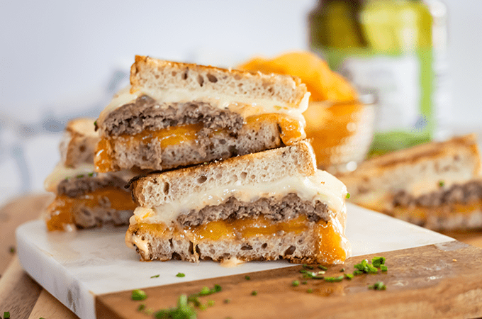 Two rye-bread sandwiches cut in half with ground beef patties, provolone and cheddar cheese and Thousand Island dressing. 