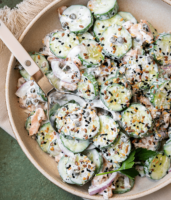 Everything bagel cucumber salad in a serving dish with a spoon. 