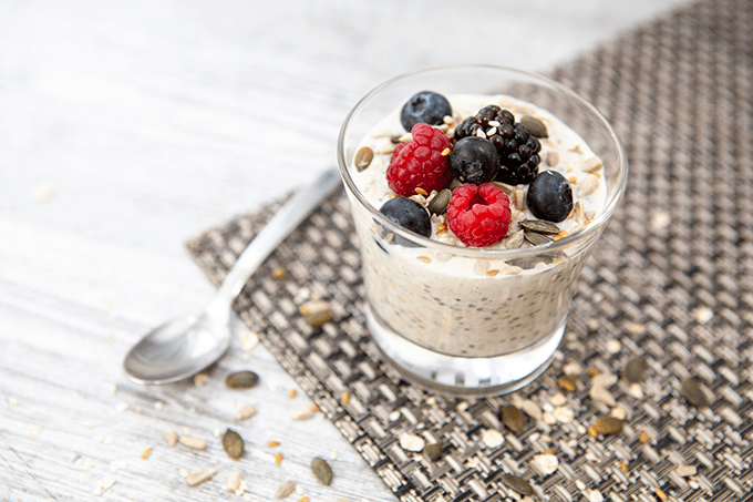 Overnight oats in a dish with flax seeds, raspberries, blueberries, and blackberries. 