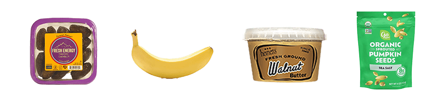 Snack items in a row including dates, bananas, walnut butter, and pumpkin seeds. 