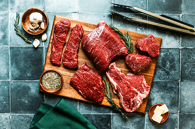 An Assortment of Raw Heinen's Premium Steaks on a Cutting Board