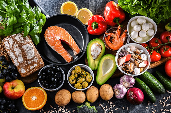 A Top Down Image of Fresh Fruits, Vegetables, Legumes, Olive Oil, Olives, and Bread