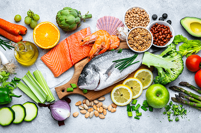 A Top Down Image of Raw Fish, Fresh Fruits, Vegetables, and Legumes