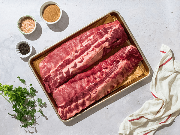 Two Racks of Raw Baby Back Ribs on a Sheet Pan