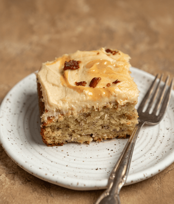 One slice of banana sheet cake with peanut butter frosting and bacon crumble topping