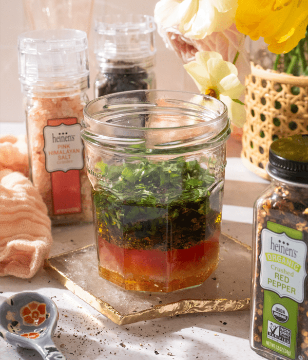 Glass jar with basil vinaigrette ingredients.