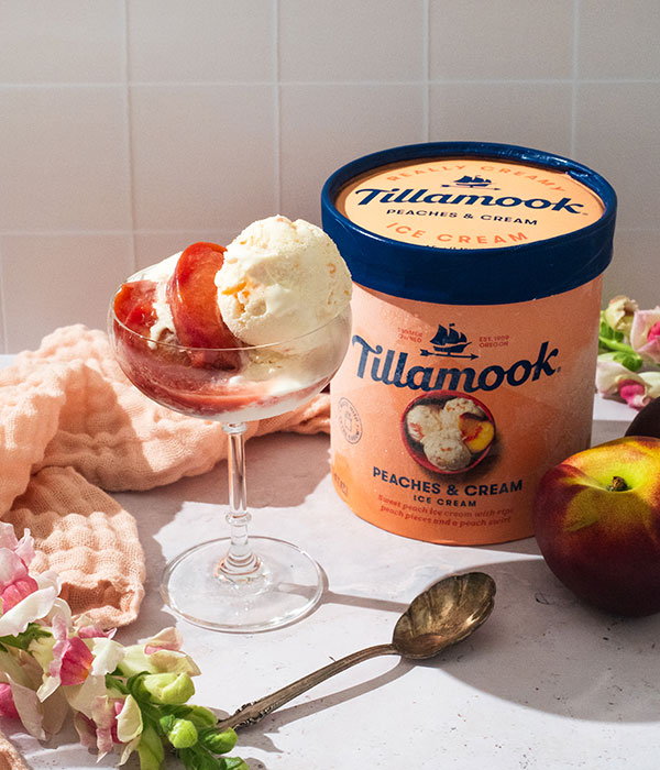 Tillamook Peaches and Cream Ice Cream with a glass of ice cream topped with brown sugar peaches
