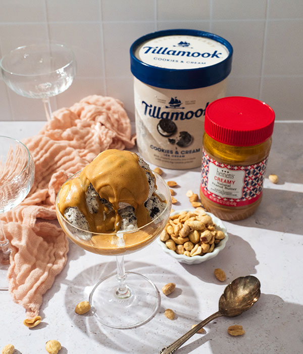 Container of Tillamook Cookies and Cream, Heinen's Creamy Peanut Butter and a dessert glass of ice cream topped with peanut butter shell