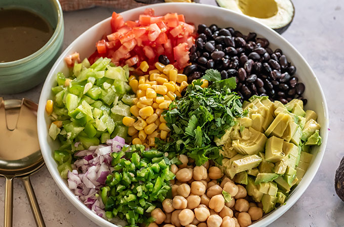 Bowl of cowboy caviar, with corn, beans, tomatoes, avocado, pepper, and onion.