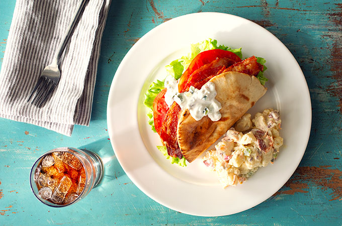 Greek BLT on a plate with a soda