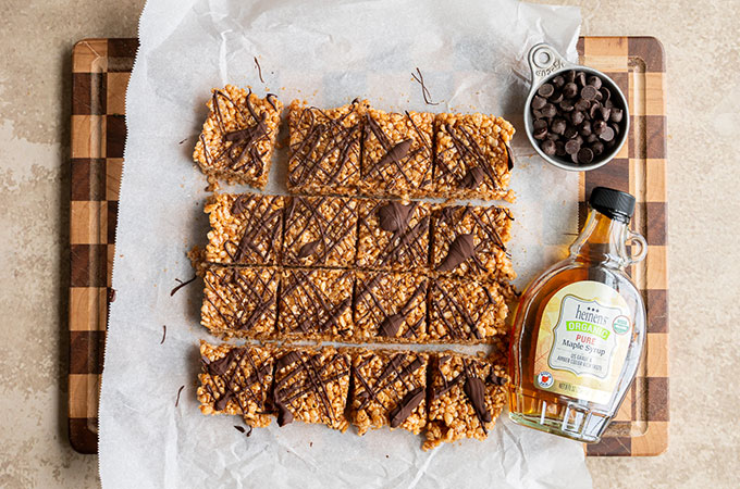 Cutting board with healthy rice crispie treats and Heinen's organic maple syrup