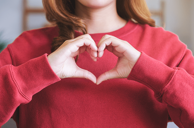 A Woman in a Red Sweatshirt Making a Heart with her Hands