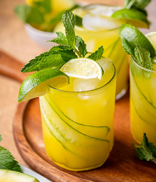 Glass of yellow watermelon agua fresca garnished with lime and mint