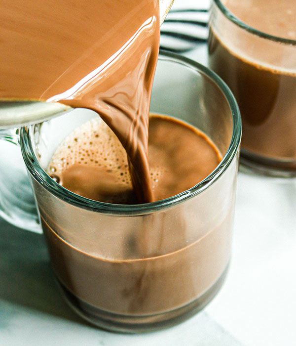 Glass of bone broth hot chocolate being poured